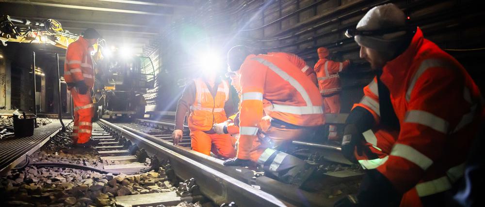 Arbeiter führen bei einer Baustellen-Begehung des Nord-Süd-Tunnels der Berliner S-Bahn Gleisarbeiten durch.