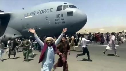 Hunderte Menschen laufen am 16. August 2021 neben einer Boeing C-17 der amerikanischen Luftwaffe in Kabul.
