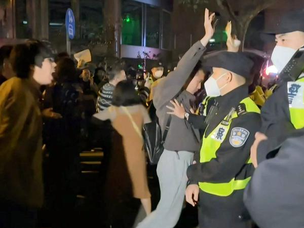 Demonstranten rufen in Shanghai Parolen, während die Polizei ihre Positionen hält (Ausschnitt aus einem Augenzeugenvideo auf AFPTV am 27. November 2022).