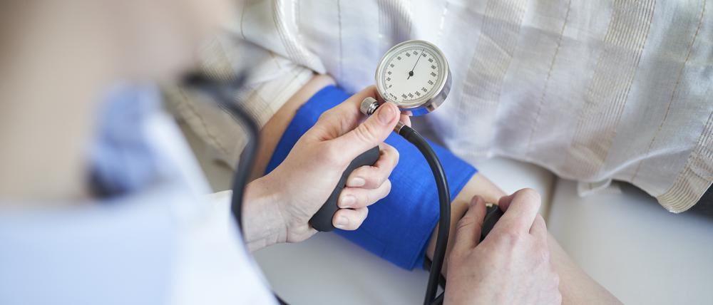 Close-up of doctor taking blood pressure of patient in medical practice