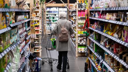 Eine Frau geht mit ihrem Einkaufswagen durch einen Supermarkt