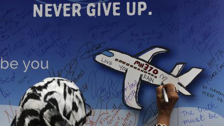 Eine Frau schreibt während einer Gedenkveranstaltung zum Flug MH370 eine Nachricht auf ein Banner. 