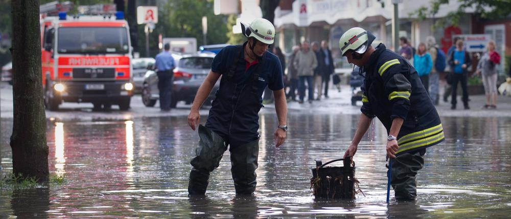 Drakestraße unter Wasser: Nach einem Starkregen im Sommer 2011 versuchen Feuerwehrmänner einen verstopften Gully frei zu bekommen.