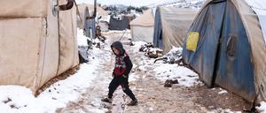 Ein Kind läuft zwischen Zelten in einem schneebedeckten Lager für Binnenvertriebene in der Nähe der Stadt Afrin.