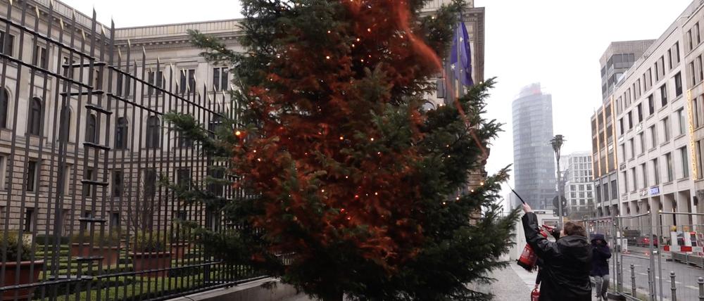 Ein Mitglied der Klimaschutzgruppe „Letzte Generation“ besprüht einen Weihnachtsbaum vor dem Bundesrat mit orangener Farbe.
