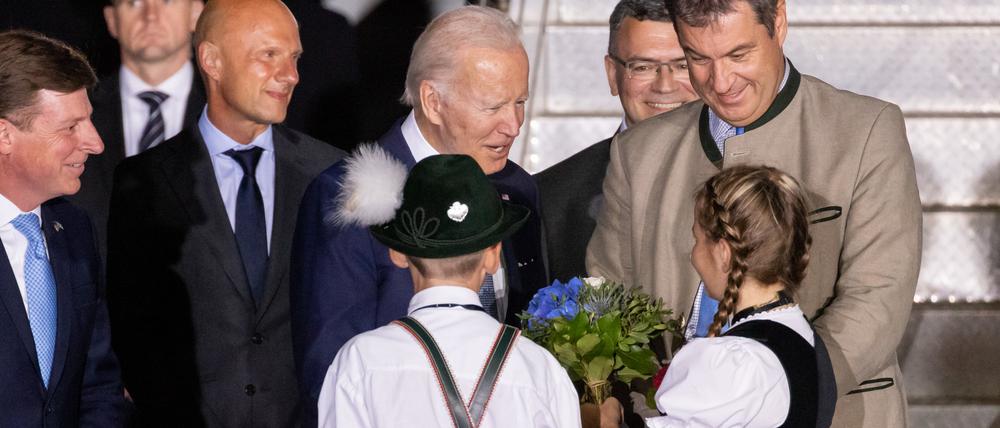 Kinder in Trachten und Marcus Söder begrüßen den US-Präsidenten Joe Biden.