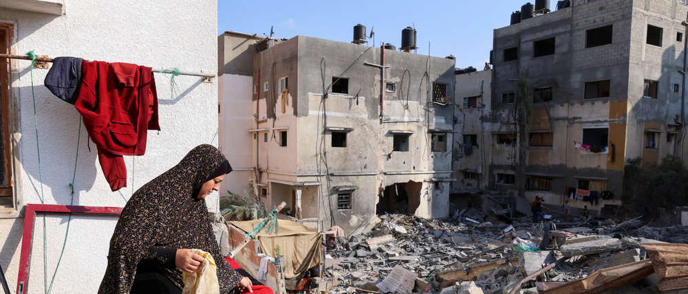 Eine palästinensische Frau hängt Wäsche vor ihrem zerstörten Haus auf. 