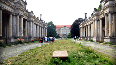 Blick durch die Kolonnaden in den Kleistpark, vorn die Gedenktafel für die Opfer des nationalsozialistischen „Volksgerichtshofs“, der auch im Kammergericht tagte, das hinten zu sehen ist.