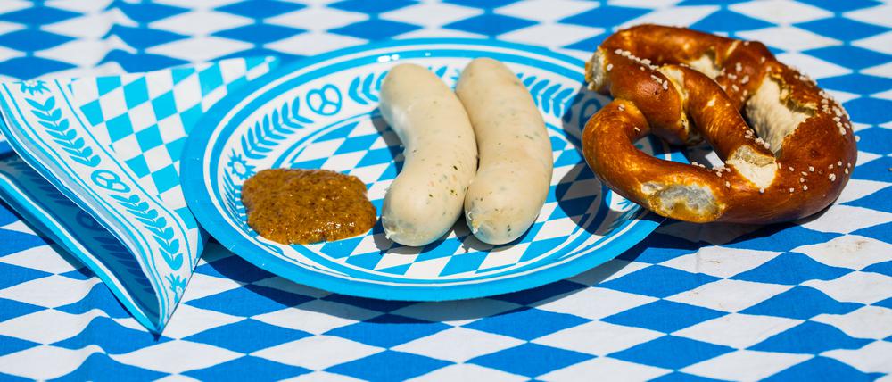 white sausage with sweet mustard and pretzel on blue white plate