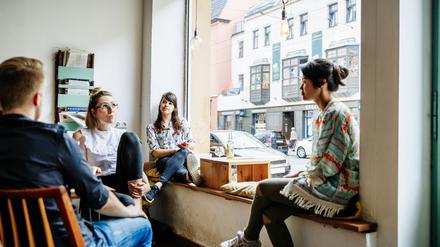 Vor einem Fenster im Café diskutiert eine Freundeskreis aus Studis, was sie gerade bewegt.