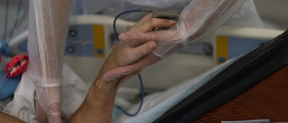 Eine Krankenschwester hält die Hand eines Coronavirus-Patienten
