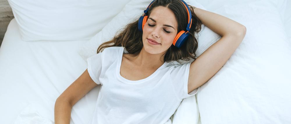 Young woman sleeping in bed at home with headphones model released Symbolfoto property released PUBLICATIONxINxGERxSUIxAUTxHUNxONLY KIJF02565