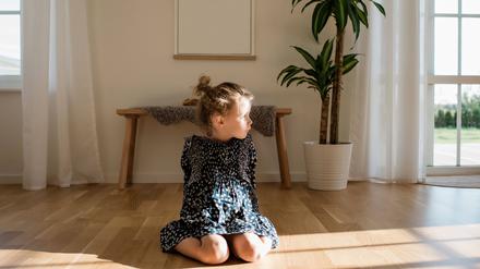 portrait of a young girl sitting alone at home looking out the window
