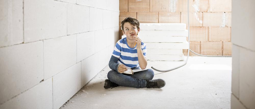 Thoughtful boy with book sitting on loft floor during renovation model released Symbolfoto property released HMEF01224 