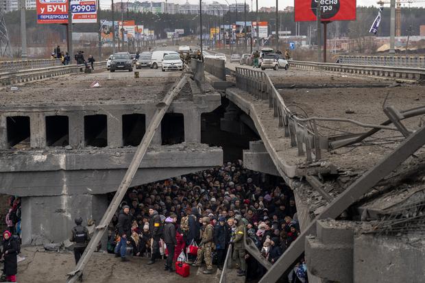Ukrainer versammeln sich am 5. März an der zerstörten Brücke von Irpin. Sie wollen den Fluss überqueren.