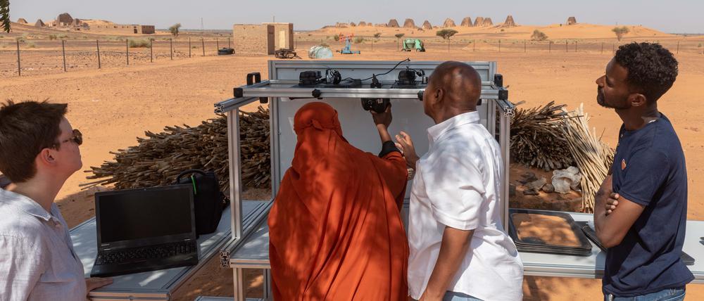 Vor den Pyramiden in Meroe, Sudan, installiert eine Museumsmitarbeiterin den Modultisch zur Fotodikumentation, den die KulturGutRetter mitgebracht haben.