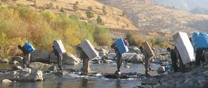 Schwere Last. Kurdische Lastenträger überqueren die Grenze durch einen Fluss in Richtung iranische Grenze. (Foto von Rahman Hassani/SOPA Images/LightRo)