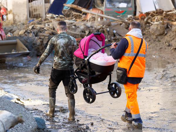 Männer tragen m 27. November 2022 einen Kinderwagen mit einem Baby nach einem Erdrutsch auf der italienischen Ferieninsel Ischia, Italien.