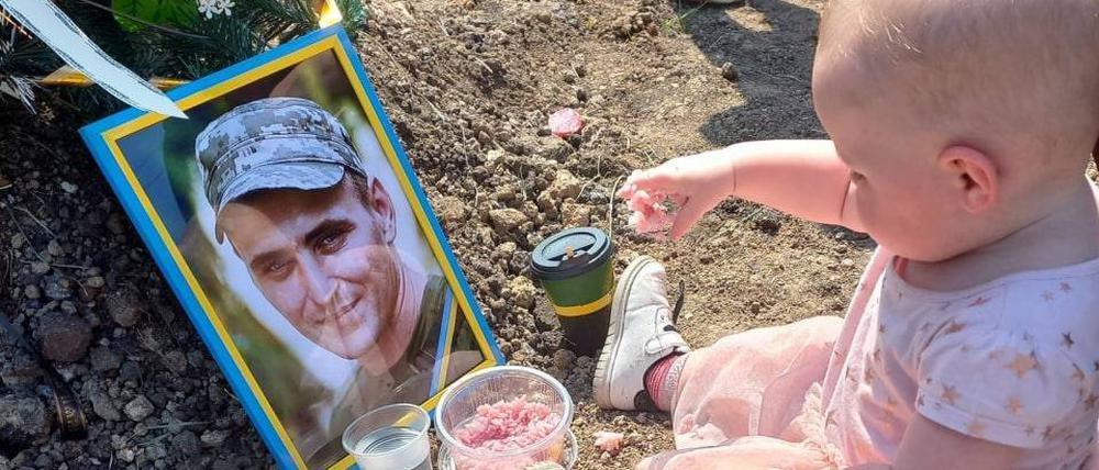 Ein ukrainisches Mädchen frühstückt am Grab seines gefallenen Vaters, das ukrainische Verteidigungsministerium verbreitet das Bild.
