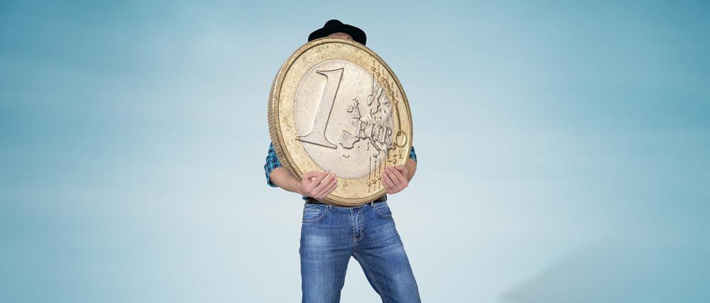 Ein Mann hält eine große, schwere Euro-Münze.