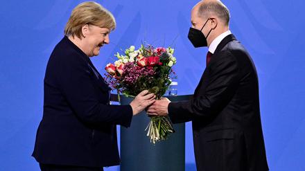 Olaf Scholz überreicht Angela Merkel einen Strauß Blumen 