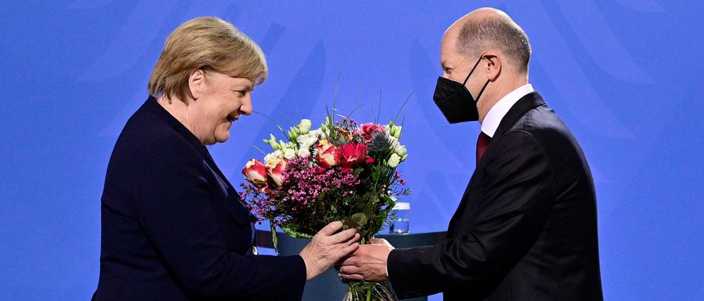 Olaf Scholz überreicht Angela Merkel einen Strauß Blumen 