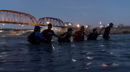 Migranten laufen Hand ind Hand durch den Rio Grande River, um aus Mexiko nach Eagle Pass in Texas zu gelangen.   