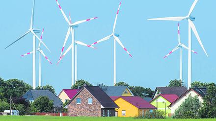 Ganz dicht stehen Windräder eines Windenergieparks hinter Einfamilienhäusern nahe Nauen (Brandenburg).