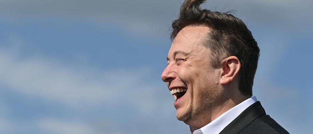 Elon Musk, Tesla-Chef, steht lachend auf der Baustelle der Tesla Gigafactory. 
