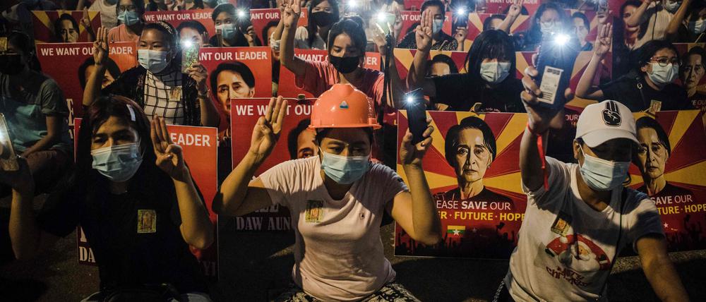 Protestierende in Myanmar halten Plakate mit Aung San Suu Kyi vor sich.