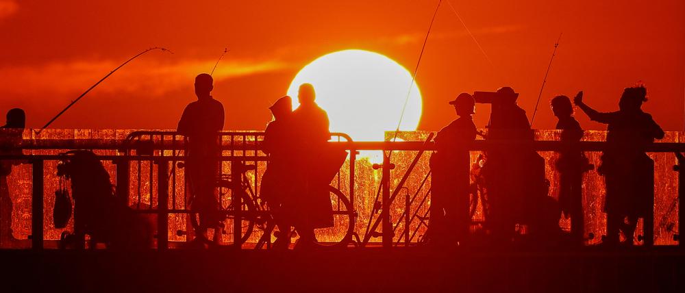 People stand on a pier during sunset in the Baltic Sea resort of Zelenogradsk in the Kaliningrad region, Russia June 23, 2022. Picture taken June 23, 2022. REUTERS/Vitaly Nevar