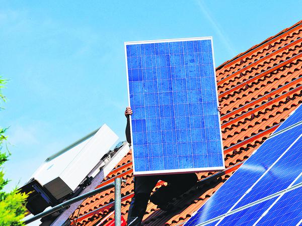 Montage eines Fotovoltaik-Moduls auf einem Hausdach.