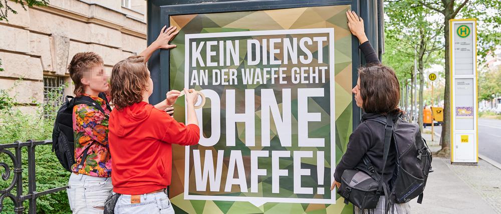 Frida Henkel klebt mit Sympathisantinnen ein Plakat der Bundeswehr mit dem von ihr abgeänderten Slogan „Kein Dienst an der Waffe geht ohne Waffe!“ vor dem Kriminalgericht in Moabit an. 