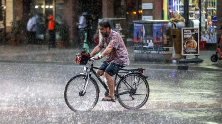 Ein Fahrradfahrer fährt bei strömendem Regen an der Potsdamer Straße, Berlin.