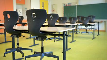 Die Stühle sind in einem leeren Klassenzimmer auf die Schulbänke gestellt.