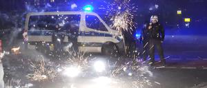 Polizeibeamte stehen hinter explodierendem Feuerwerk. (Zu dpa "Silvester-Krawalle: Vor allem Ältere halten hohe Strafen für richtig") +++ dpa-Bildfunk +++