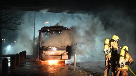 Feuerwehrleute löschen an der Neuköllner Sonnenallee einen Reisebus, der von Unbekannten angezündet worden war.