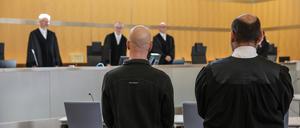 Der Angeklagte (l, vorne) steht neben seinem Anwalt Marvin Schroth (r) im Gerichtssaal. 