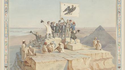 Die Mitglieder der Expedition auf der Cheops-Pyramide. Um das Bild herum sieht man in Hieroglyphen eine Widmung an König Wilhelm IV. von Richard Lepsius.