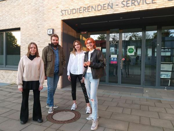 Drei Studentinnen und ein Student stehen vor dem Studierenden-Service-Center der Freien Universität Berlin.