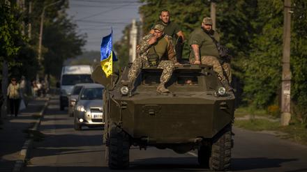 Soldaten der ukrainischen Armee sitzen auf einem gepanzerten Militärfahrzeug.