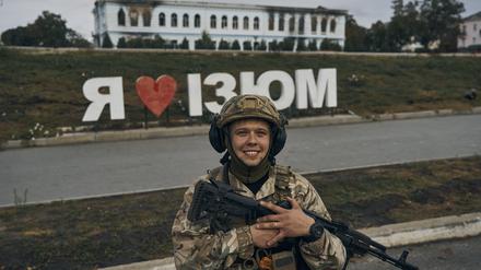 Ein ukrainischer Soldat lächelt vor einem Schild mit der Aufschrift „Ich liebe Izium“ in der befreiten Stadt Izium in der Region Charkiw. 