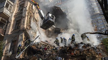 Feuerwehrleute räumen Trümmer zur Seite nach dem Beschuss auf Gebäude durch eine Drohne. 