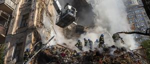 Feuerwehrleute räumen Trümmer zur Seite nach dem Beschuss auf Gebäude durch eine Drohne. 