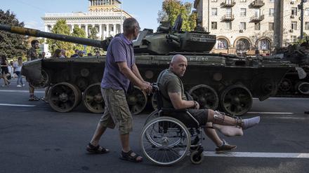 Ein Mann schiebt einen verwundeten ukrainischen Soldaten in einem Rollstuhl durch die Straßen von Kiew.