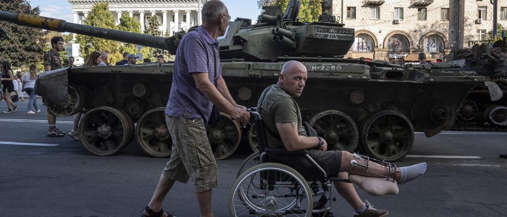 Ein Mann schiebt einen verwundeten ukrainischen Soldaten in einem Rollstuhl durch die Straßen von Kiew.