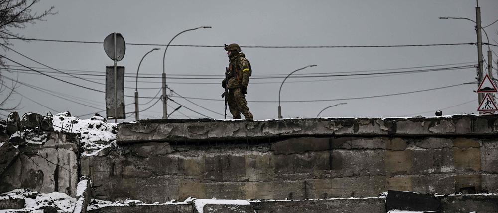 Ein ukrainischer Soldat steht an einer zerstörten Brücke im Norden von Kiew.
