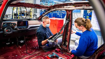 VW-Mitarbeiterinnen und Mitarbeiter werden in einem Trainingsbereich für die Produktion von Elektroautos geschult.