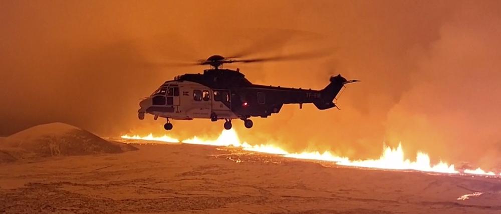 Ein Hubschrauber überfliegt einen Vulkanausbruch in Island.