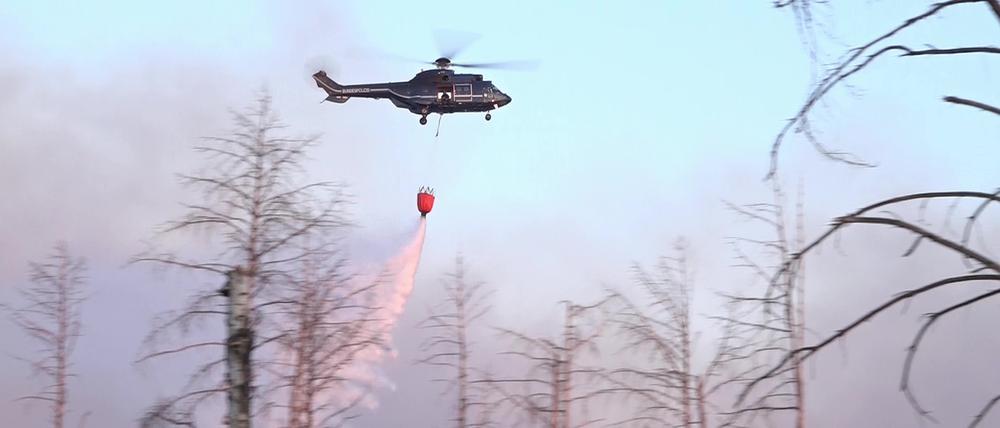 Ein Löschhubschrauber wirft Wasser ab über einem Waldbrand in einem munitionsbelasteten Gebiet bei Jüterbog (Landkreis Teltow-Fläming). 